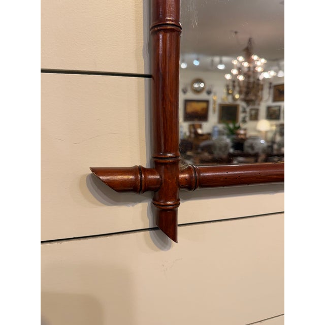 This is a French antique faux-bamboo wall mirror with a hand-carved wood frame. The frame is wood that has been shaped and...