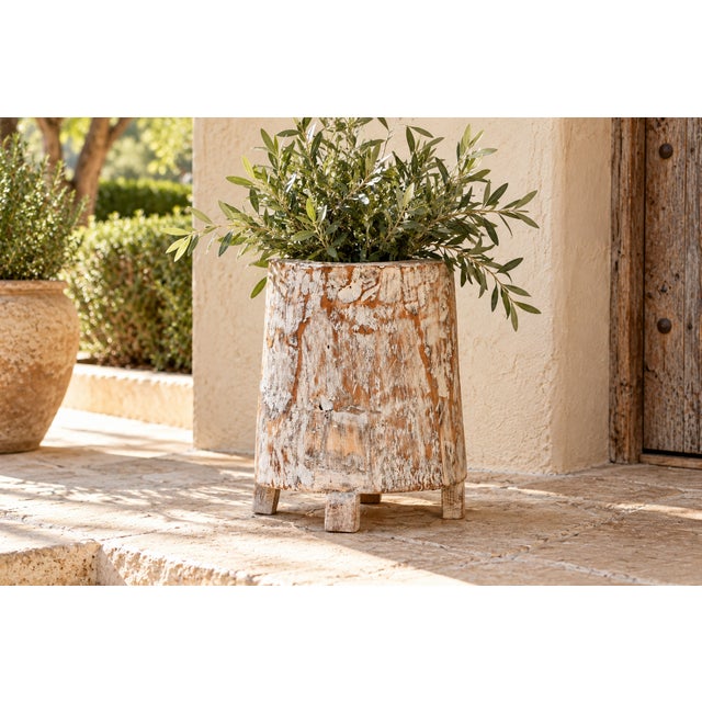 A thick-walled cylinder cut from a single block of wood tapers gently from base to rim, standing on four short block feet...