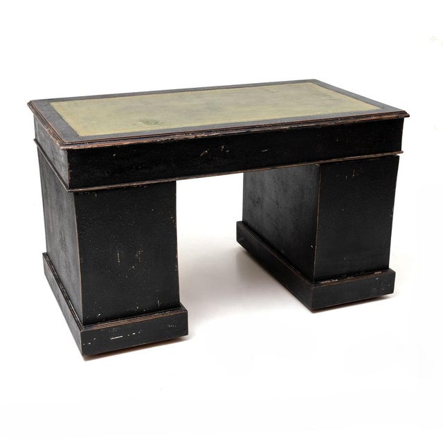 Rectangular desk with a black finish and an inset leather writing surface. The front features a total of nine drawers...