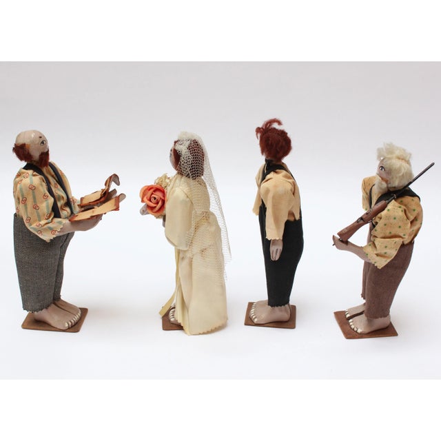 Crude hand-carved and painted wedding party figures (bride, groom, officiant - likely a preacher, and witness - presumably...