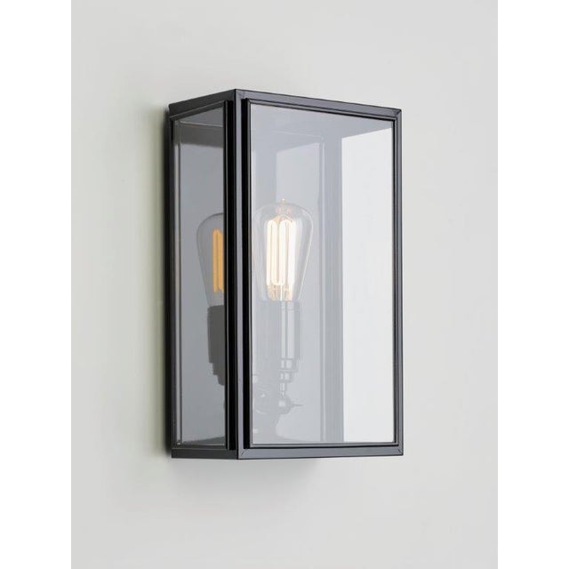 Wall light in brass lacquered in color with outside fitted clear or frosted glass and spring closure. For indoor and...