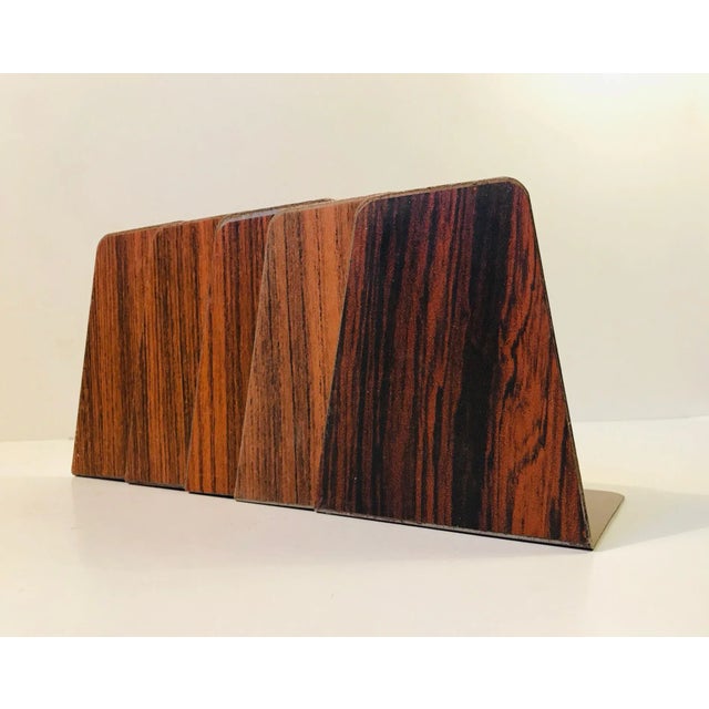 A set of 5 enameled steel bookends with applied teak and rosewood superficial veneer/foil. Manufactured in Denmark during...