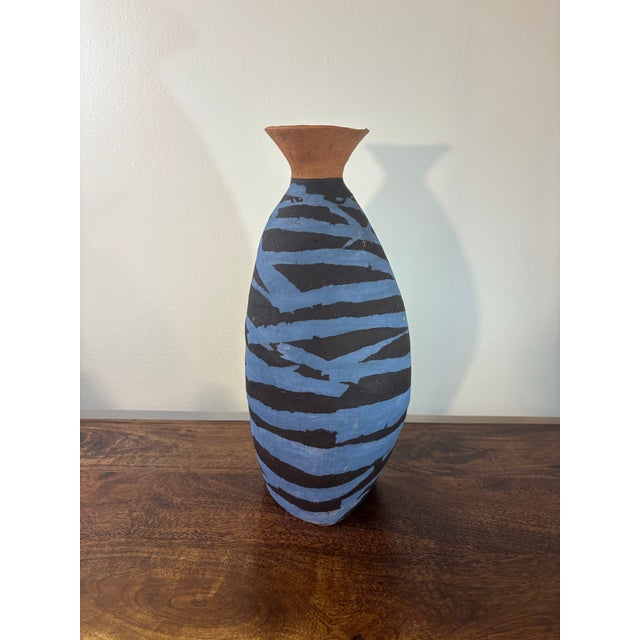 A striking hand-thrown Brazilian studio pottery vase featuring an expressive hand-painted blue and black striped...