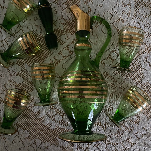 E ight piece vintage, mid century modern green blown glass decanter (1), stopper (1), and glassware (6) with gold gilding...