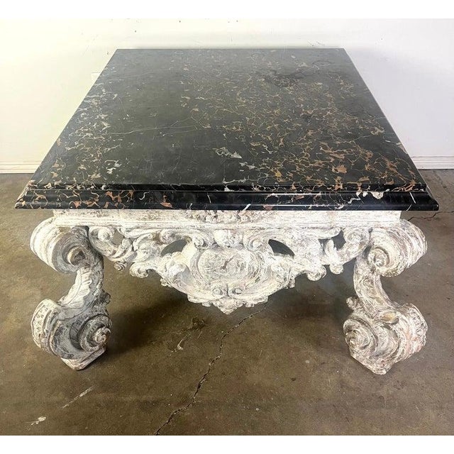 Monumental rectangular, ornate Rococo style coffee table featuring a dark, polished marble top with natural veining and...