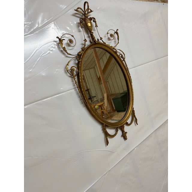 High quality oval Giltwood and carved gesso wall mirror with Urn decoration and scrolling accents possibly by Friedman...
