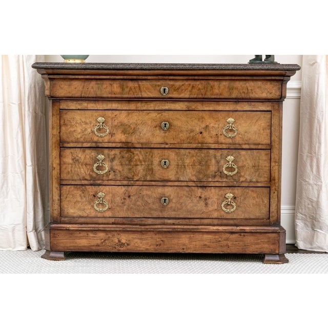 An early 19th century French Charles X figured walnut chest of drawers with a shaped marble top, three drawers with fine...