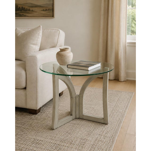 A distinctive vintage sculptural side table featuring a round clear-glass top supported by an architectural wooden tripod...