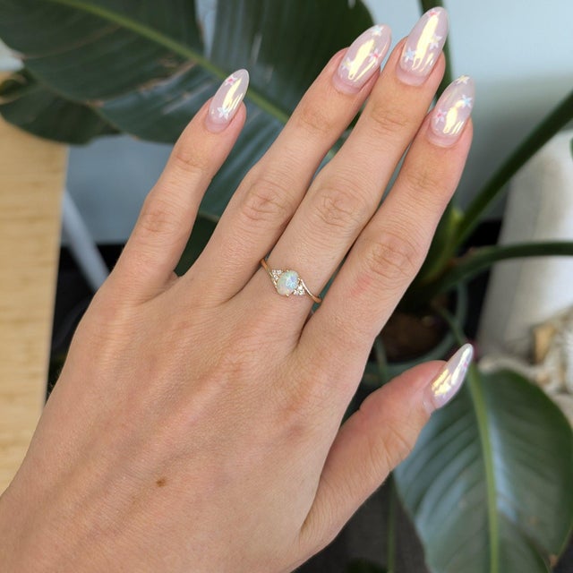 A natural Ethiopian opal shimmers with flashes of rainbow play-of-color in this cabochon ring, accented with diamonds in...