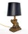 A gold and silver highlighted bronze toned petit resin figural table lamp featuring an elephant with his trunk showing in...