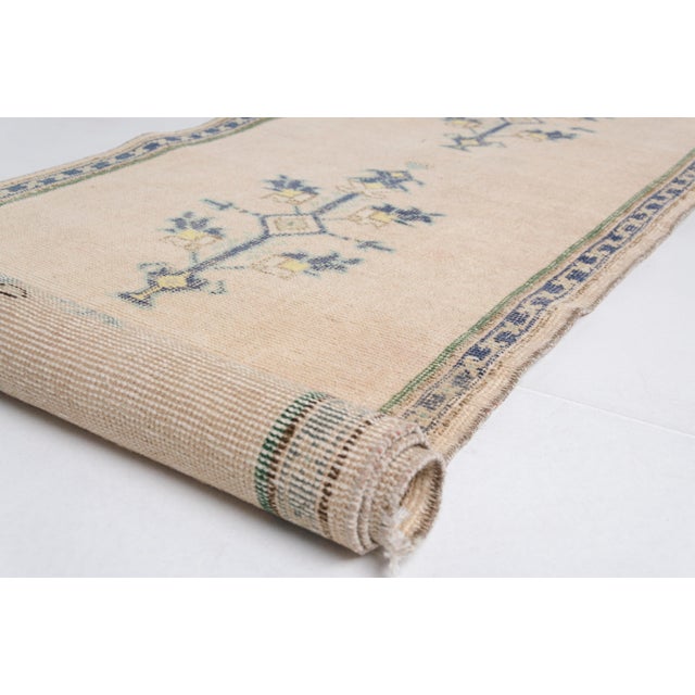 This is a vintage Turkish Oushak rug from the Mid 20th Century. The piece was hand-knotted.