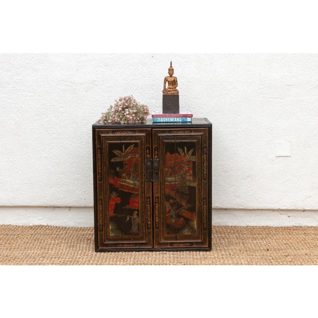 This antique Chinese cabinet, adorned with captivating painted scenes, invites you to step into a world of vibrant...