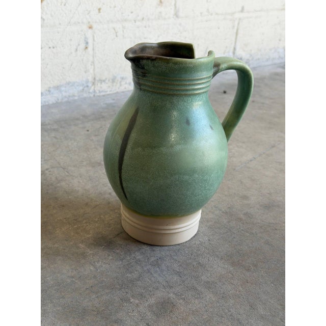 Vintage Mid-Century Modern ceramic pitcher jar features a striking organic aesthetic with a bulbous silhouette and an...