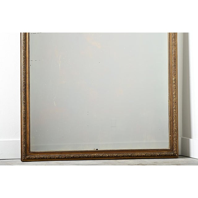 A dramatic French, late 19th century gold gilt mirror with original mirror glass framed by delicately carved foliate...