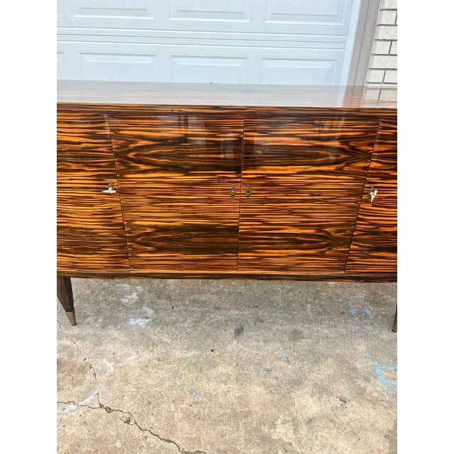 A striking French Art Deco Modern sideboard crafted in exotic Macassar ebony veneer, showcasing dramatic bookmatched grain...