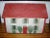 Antique paint decorated doll's house in shades of white, red and green with painted shutters and shrubs. Back is open and...