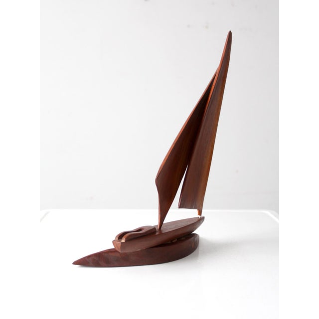 Bring mid-century modern style and nautical flair to your space with this vintage wooden sailboat sculpture. Featuring...