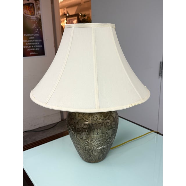 Design Plus Gallery presents the Gilded Botanical Relief Table Lamp. The rounded body displays an antiqued bronze and...