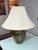 Design Plus Gallery presents the Gilded Botanical Relief Table Lamp. The rounded body displays an antiqued bronze and...