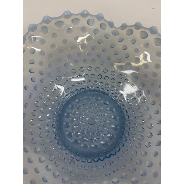 Vintage blue opalescent Fenton glass bowl featuring a raised hobnail pattern, scalloped ruffled rim, and circular footed...