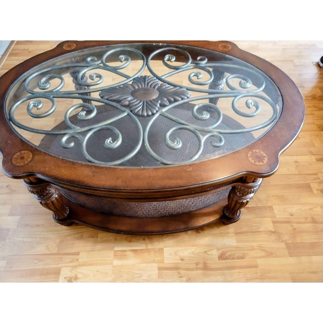 Antique wooden coffee table, oval-shaped, featuring glass and bronze ornamentation, with two tiers. Coffee-brown color.