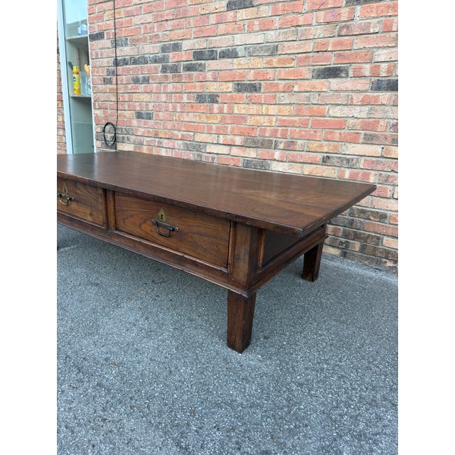 This is a 19th Century French dark oak coffee table featuring two drawers, both with brass pull hardware and keyhole...