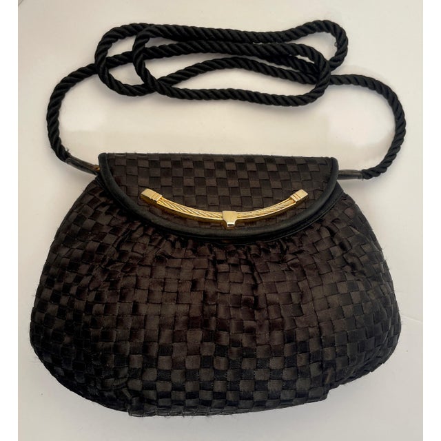 A handsome evening bag with a gold colored metal details, leather trim, and magnetic button closure. It has a metal ID bar...