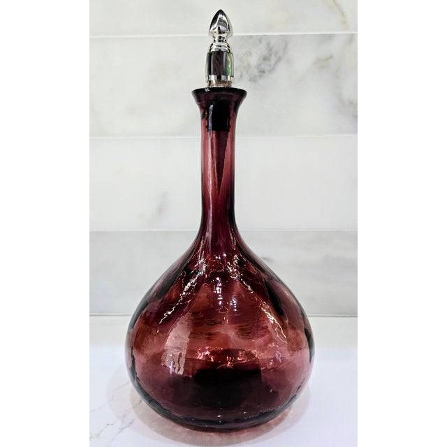 This sculptural amethyst art glass bottle / decanter features a pear‑shaped body with vertical optic ribbing and a slender...