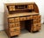 American Colonial style roll top desk in a medium wood tone. The desk pedestal features three drawers to either side and...