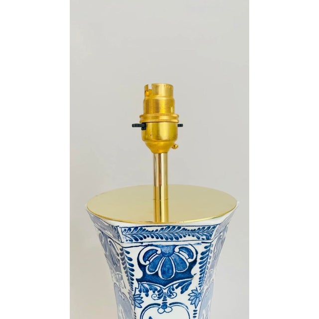 A 20th century delft table lamp made from a boch for royal sphinx vase. The lamp is off white featuring decorations in...