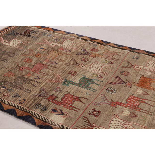 Hand-knotted in wool circa 1950-1960, this 5x8 vintage Persian Gabbeh rug is a monumental achievement in tribal pictorial...