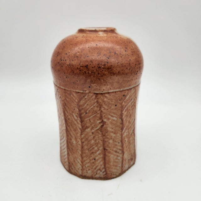 Faceted stoneware vase with incised chevron pattern, speckled rust-brown shino-style glaze with white drip accents, domed...