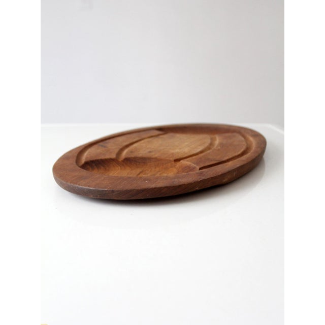 Vintage 1960s teak carving board with a generous oval form, deeply carved juice groove, and sculptural wells at either...