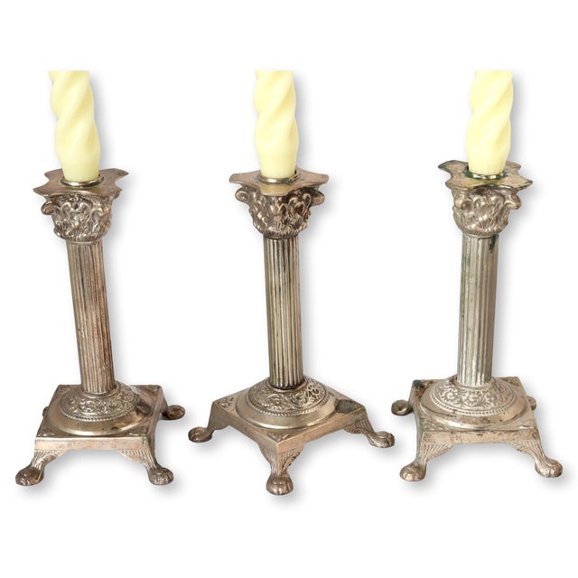 Set of three metal candlestick holders with footed bases. They are heavy and stable. Cast metal with a silver finish....