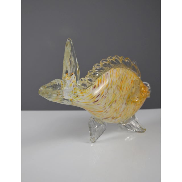 Elegant handcrafted Murano glass fish sculpture. This decorative piece features a vibrant body with yellow, orange, and...