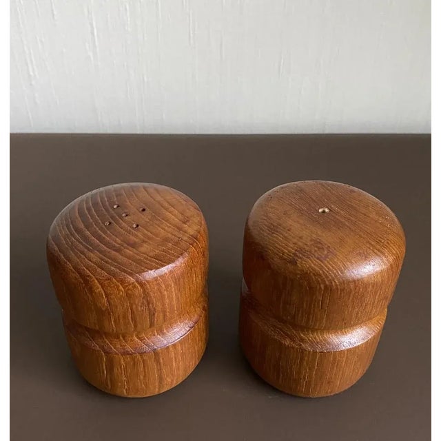 Vintage pair of teak salt and pepper shakers with sculpted detail which fits the hand. Rubber stoppers to their bases. In...