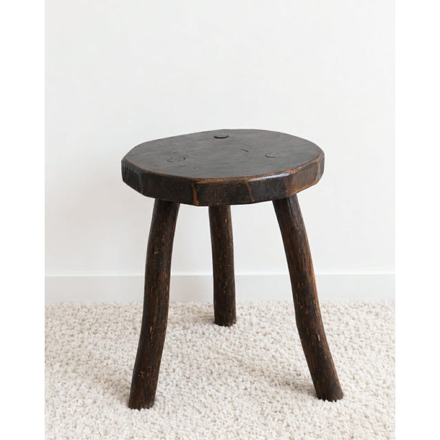 Vintage Brutalist tripod stool in solid wood, circa 1950. Slightly curved circular seat resting on three wooden legs....