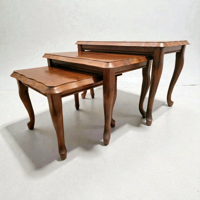 A refined and beautifully preserved three-piece nesting table set, exquisitely crafted from solid hardwood and presented...