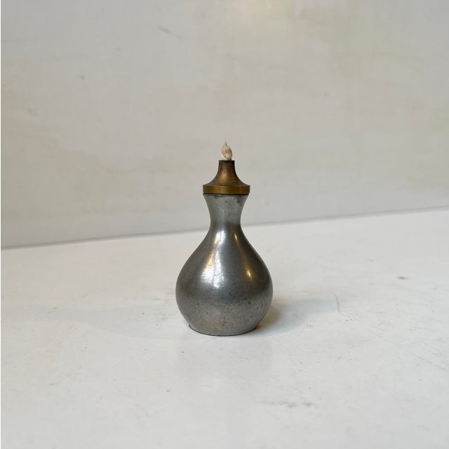 A very small oil lamp made by Just Andersen in Denmark during the 1930s. Its corpus is made from pewter while its burner...