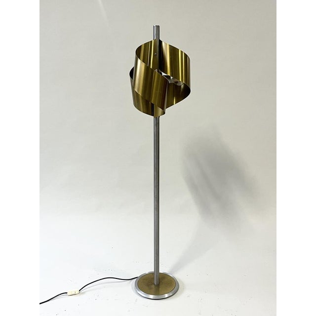 Italian floor lamp produced in the 1970s. Constructed from brushed steel with brass accents. When illuminated, the...