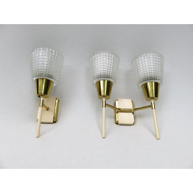 A few elegant wall lights - stylized torches - from the 1950s in the color combination brass with beige. One of the lights...