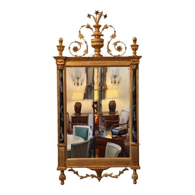 A striking pair of giltwood mirrors with elaborate carved and gilt cresting. Each mirror is topped with a central flaming...