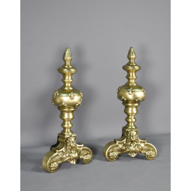 Sourced in Southwest France, this splendid pair of fire dogs / andirons feature decorative embellished flowers to the tops...