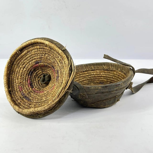 An Ethiopian leather-wrapped lunch box constructed from coiled grass and fully encased in hide. The form features a fitted...