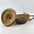 An Ethiopian leather-wrapped lunch box constructed from coiled grass and fully encased in hide. The form features a fitted...