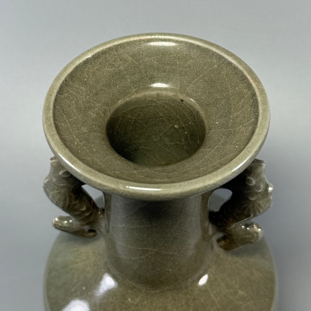 This antique Chinese Longquan celadon vase features a pair of finely molded fish-dragon (makara) handles on the neck. The...