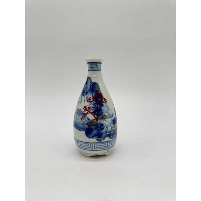 A beautiful antique Japanese porcelain sake bottle, featuring a classic blue-and-white hand-painted landscape depicting...