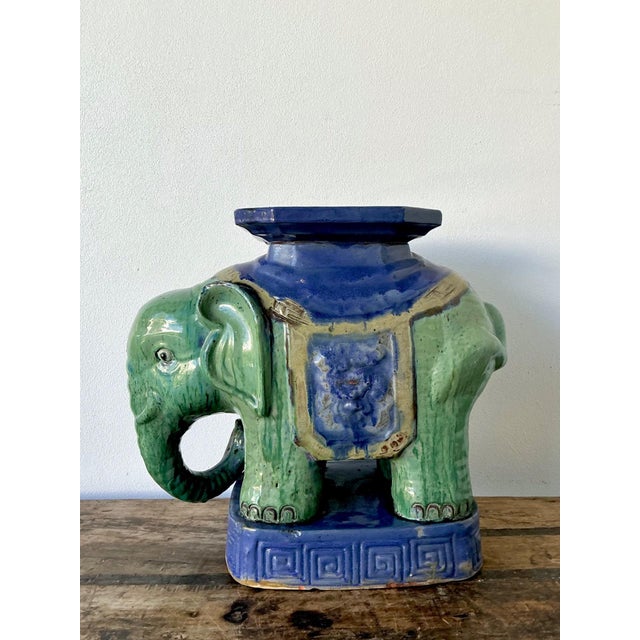 This vintage glazed ceramic elephant low stool is a vibrant celebration of sculptural form and decorative artistry,...