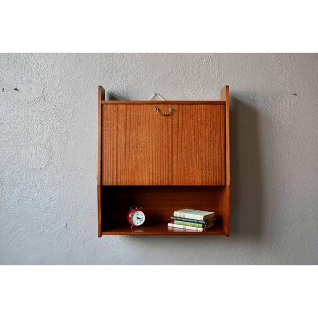 This wall-mounted secretary desk, or suspended desk, dates from the 1960s. with its deep teak finish and clean lines, it's...