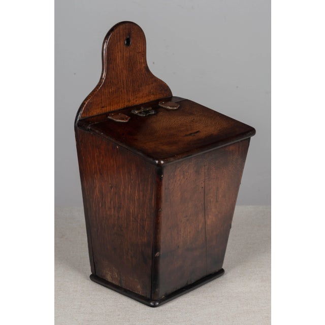 An early 19th century French boite à sel, or salt box, made of solid oak. Hinged lid with tacked leather tabs. A simple...